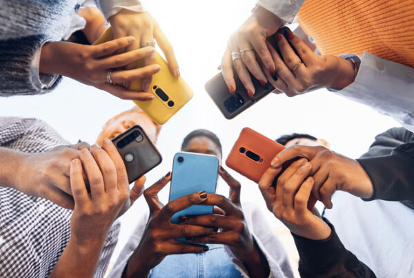 Teenagers standing in a circle using their cell phones.