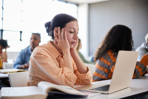 Female sitting at a table and looking distracted during a lesson in a classroom